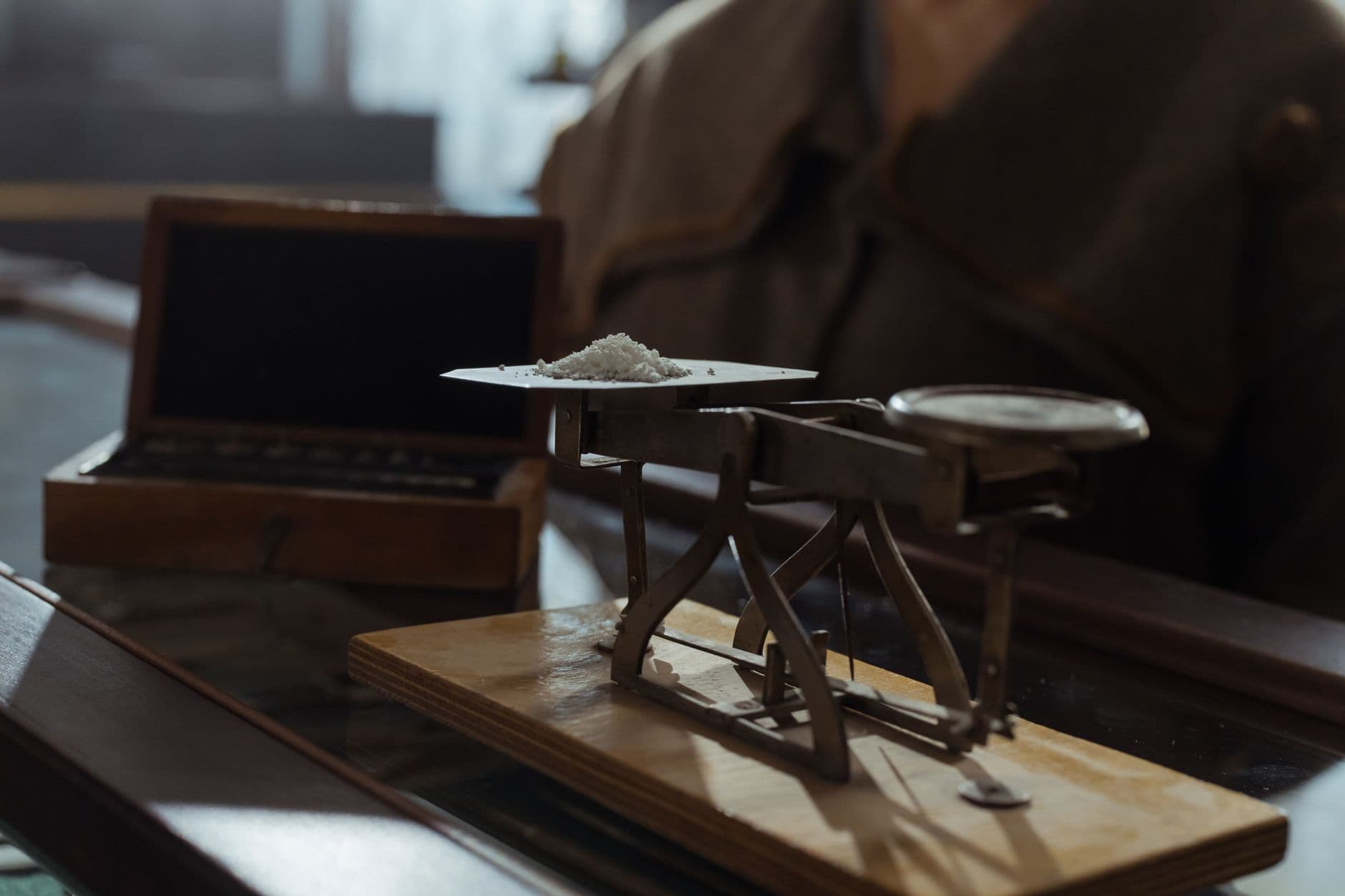 Classic vintage weighing scale with a small heap of white powder placed indoors on a wooden surface.