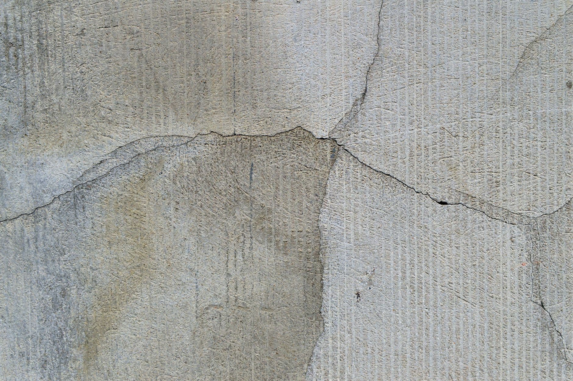 Detailed view of a cracked, textured concrete wall, perfect for backgrounds.